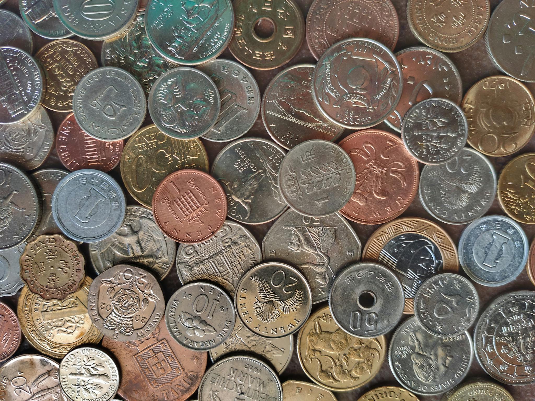 Diverse collection of world coins in a flat lay arrangement, showcasing different currencies and designs.
